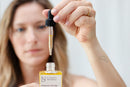 Elodie's Naturals: Woman lifting oil dropper from bottle