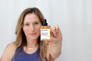 Elodie's Naturals: Woman holding golden serum bottle