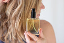 Elodie's Naturals: Woman holding body oil beside her hair