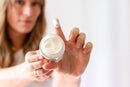 Elodie's Naturals: Woman holding open lotion jar