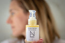 Elodie's Naturals: Woman holding a Jojoba Nectar Vitamin C serum bottle