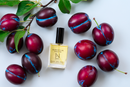 Elodie's Naturals: Body oil bottle surrounded by plums